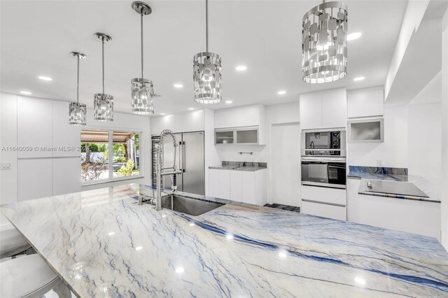 kitchen with white cabinets, stainless steel oven, sink, and decorative light fixtures