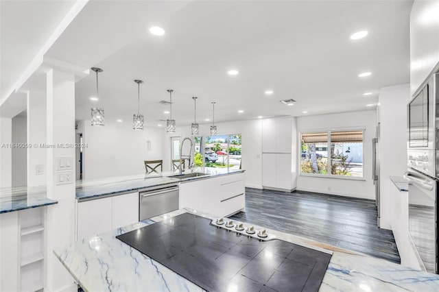 kitchen featuring appliances with stainless steel finishes, hanging light fixtures, light stone countertops, white cabinets, and sink