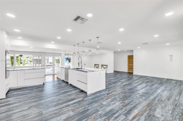 kitchen featuring dark hardwood / wood-style flooring, white cabinets, dishwasher, an island with sink, and sink