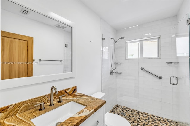 bathroom with toilet, vanity, and a shower with shower door