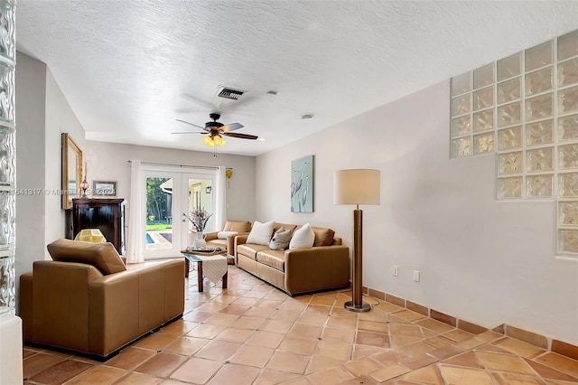 living room with a textured ceiling, light tile patterned floors, ceiling fan, and french doors