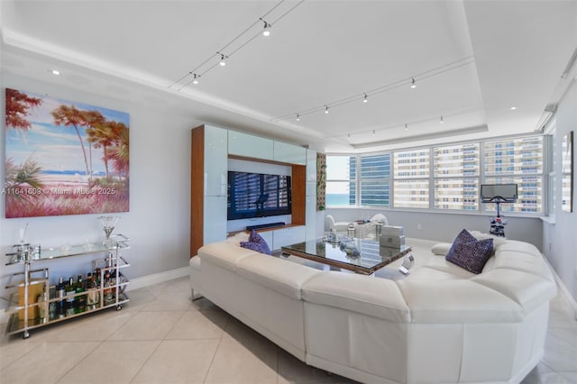 tiled living room featuring a raised ceiling and rail lighting