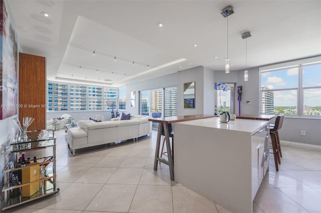 kitchen featuring a kitchen island, a breakfast bar, pendant lighting, and light tile patterned floors