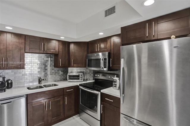 kitchen with light tile patterned flooring, sink, decorative backsplash, stainless steel appliances, and dark brown cabinets