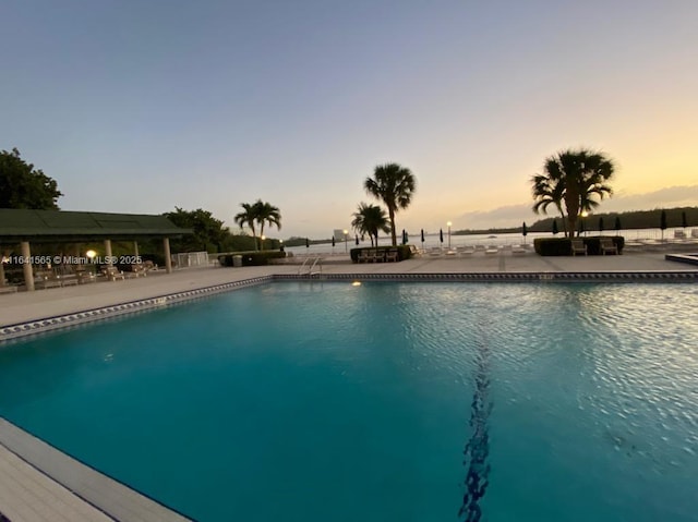 pool at dusk with a patio area