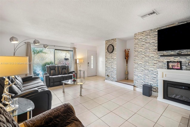 living room featuring a fireplace, a textured ceiling, and light tile patterned floors