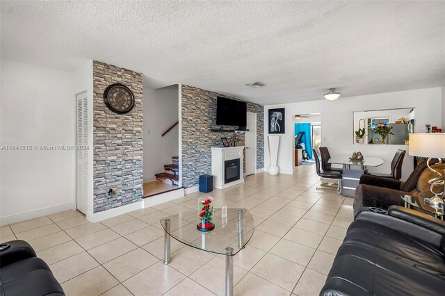 living room with light tile patterned floors, a fireplace, and a textured ceiling