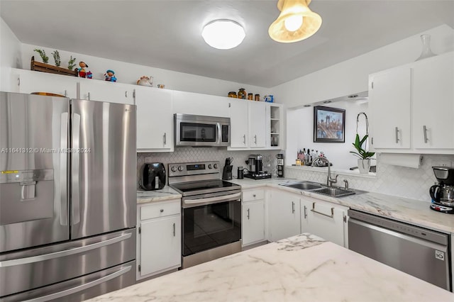 kitchen featuring appliances with stainless steel finishes, white cabinets, light stone countertops, backsplash, and sink