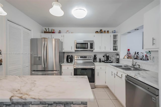 kitchen featuring appliances with stainless steel finishes, sink, light tile patterned floors, and white cabinets