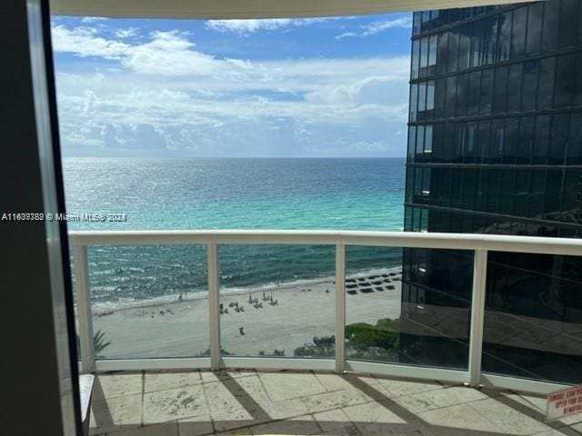 balcony featuring a beach view and a water view