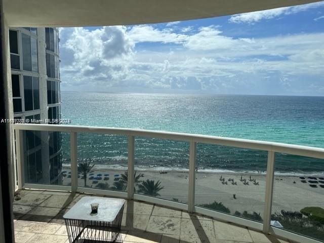 balcony with a water view and a view of the beach