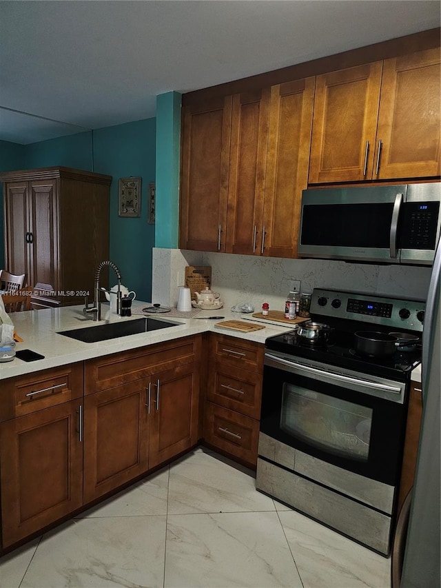 kitchen featuring decorative backsplash, sink, kitchen peninsula, and stainless steel appliances