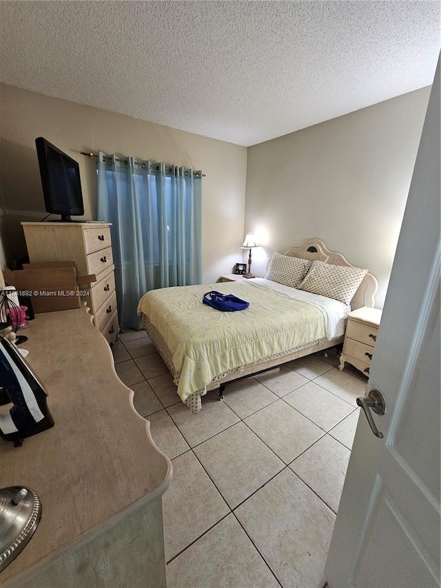 bedroom featuring light tile patterned floors and a textured ceiling