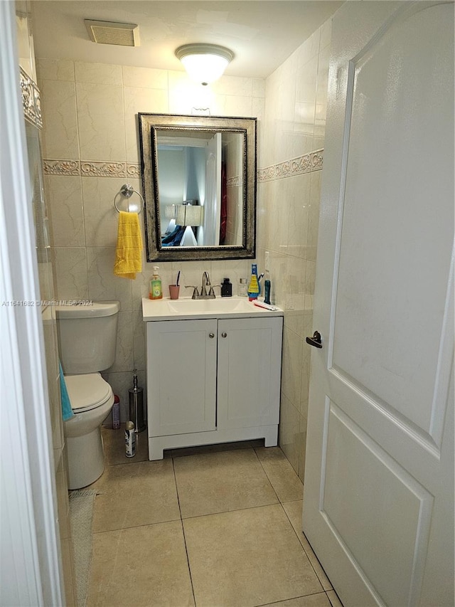 bathroom with tile patterned flooring, vanity, toilet, and tile walls