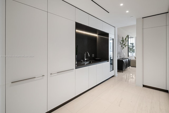 kitchen featuring tasteful backsplash, white cabinetry, and sink