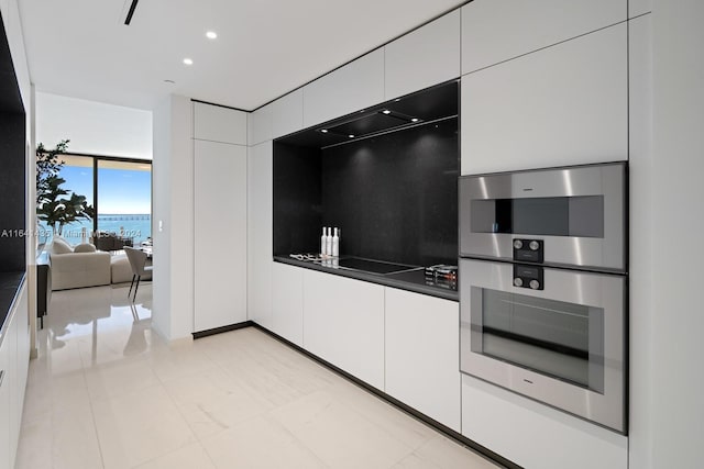 kitchen with floor to ceiling windows, black electric stovetop, white cabinetry, and double oven