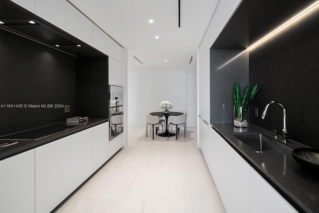 kitchen with tasteful backsplash, sink, dark stone countertops, white cabinets, and oven