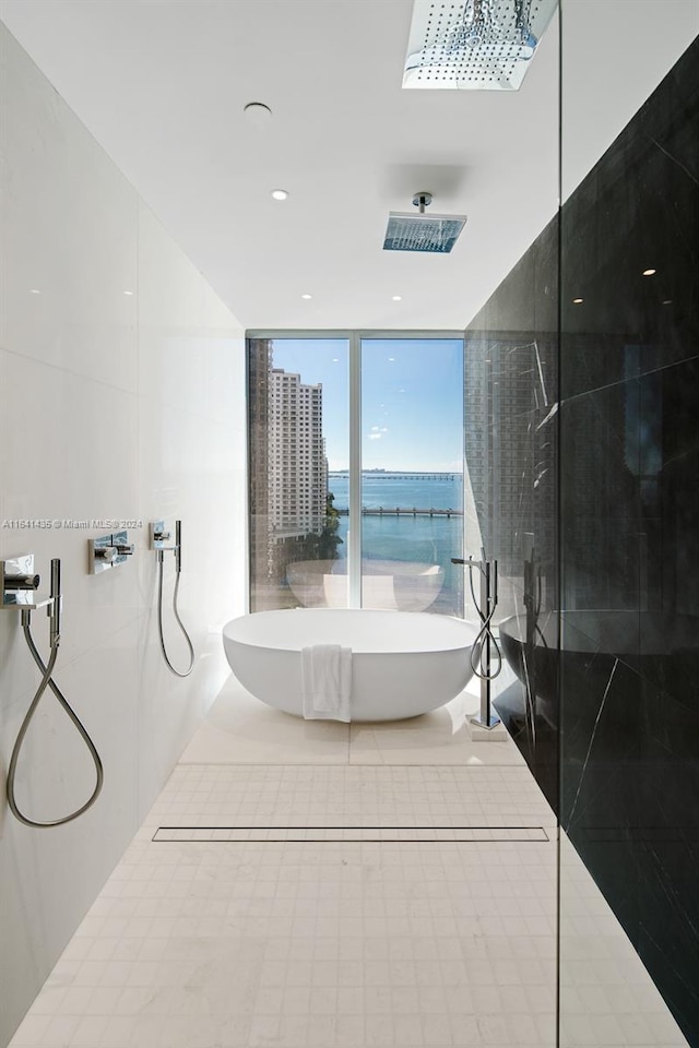 bathroom featuring a water view, a wall of windows, and independent shower and bath