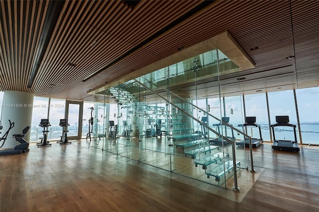 workout area featuring floor to ceiling windows, a water view, and wood-type flooring