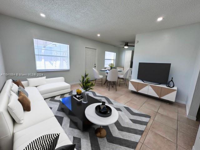 living room featuring ceiling fan, light tile patterned floors, and a textured ceiling