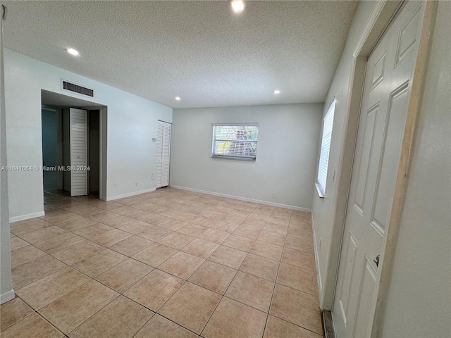 empty room with a textured ceiling and light tile patterned floors