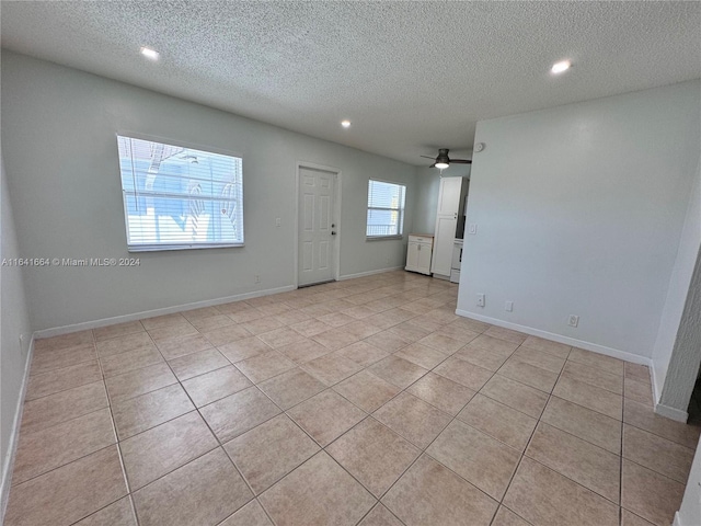 tiled spare room with a textured ceiling and ceiling fan