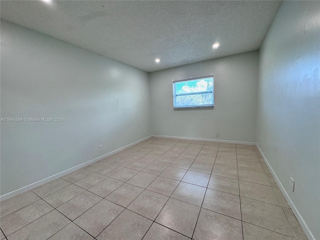 empty room featuring a textured ceiling and light tile patterned flooring