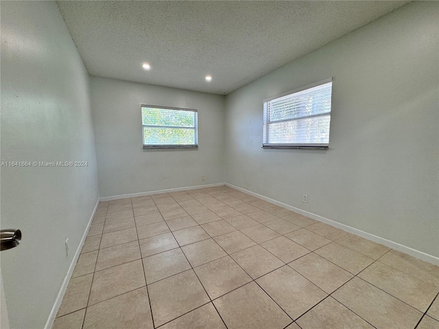 tiled spare room featuring a textured ceiling