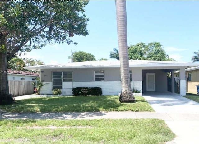 1005 NE 2nd St, Hallandale Beach, FL 33009 - ranch-style house featuring driveway, fence, an attached carport, a front yard, and stucco siding