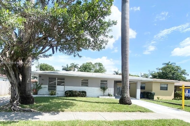 1005 NE 2nd St, Hallandale Beach, FL 33009 - single story home with stucco siding, a front lawn, a carport, and concrete driveway