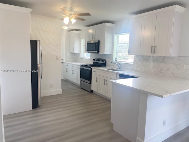 kitchen with kitchen peninsula, appliances with stainless steel finishes, backsplash, and white cabinetry