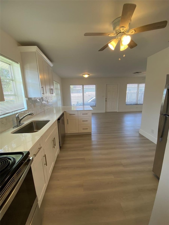 kitchen with white cabinets, sink, appliances with stainless steel finishes, tasteful backsplash, and kitchen peninsula