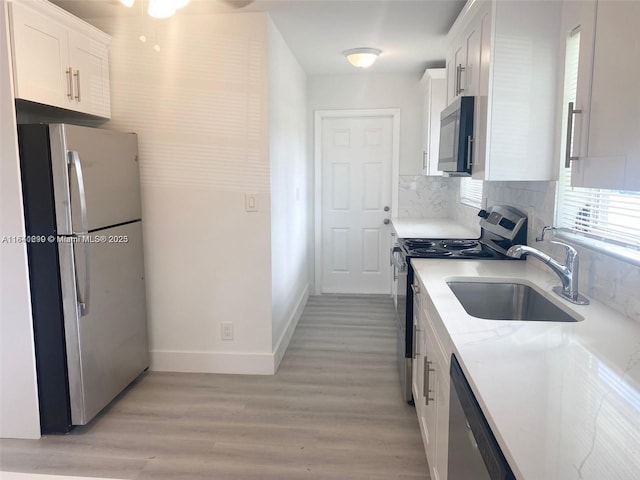 kitchen featuring white cabinets, light stone countertops, sink, and appliances with stainless steel finishes