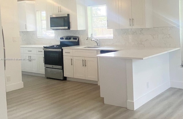 1005 NE 2nd St, Hallandale Beach, FL 33009 - kitchen featuring white cabinets, appliances with stainless steel finishes, a sink, and light wood-type flooring