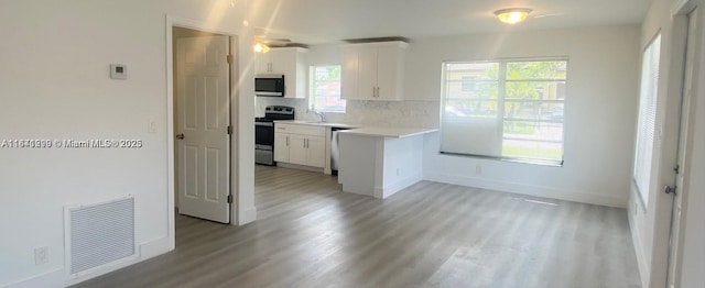 kitchen featuring backsplash, light hardwood / wood-style floors, white cabinetry, and stainless steel appliances