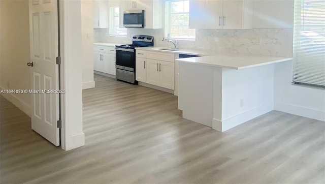 kitchen with sink, light wood-type flooring, tasteful backsplash, white cabinetry, and stainless steel appliances