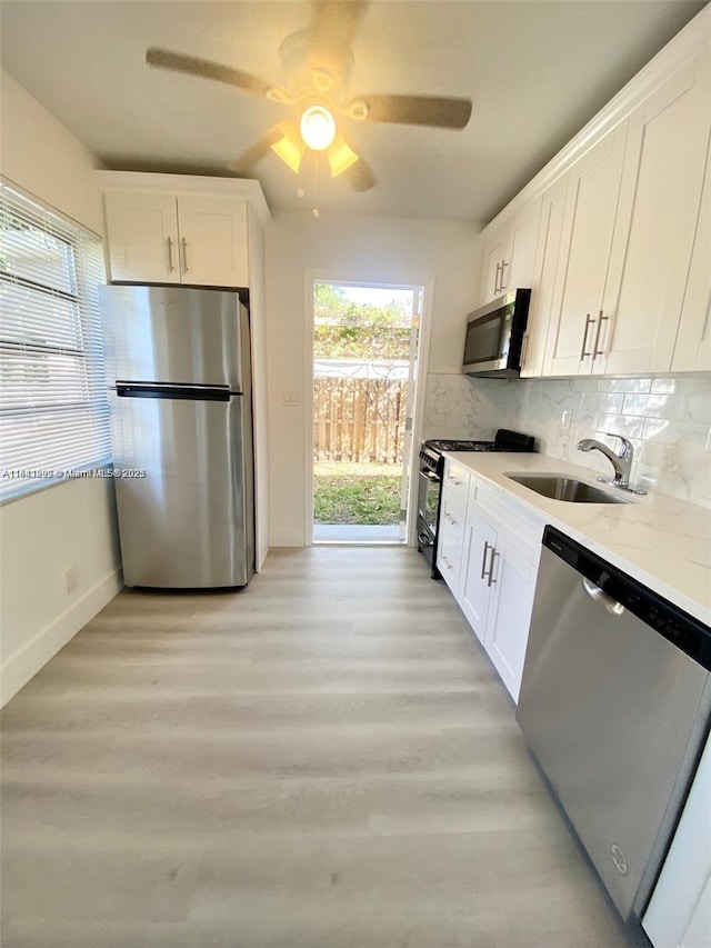 1005 NE 2nd St, Hallandale Beach, FL 33009 - kitchen featuring a sink, light wood-style floors, stainless steel appliances, white cabinets, and baseboards