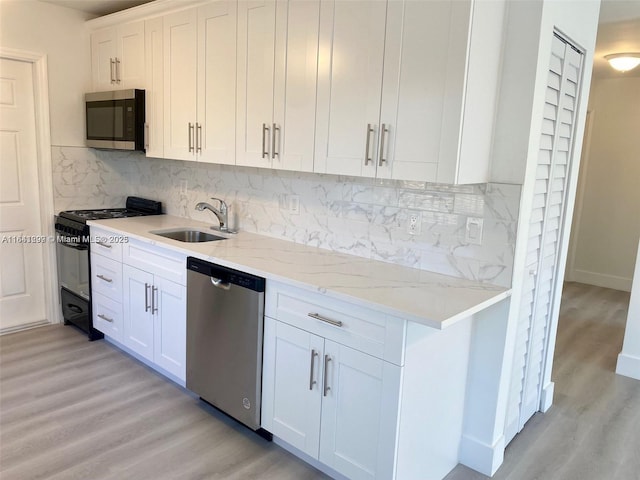 kitchen with decorative backsplash, sink, white cabinets, and stainless steel appliances