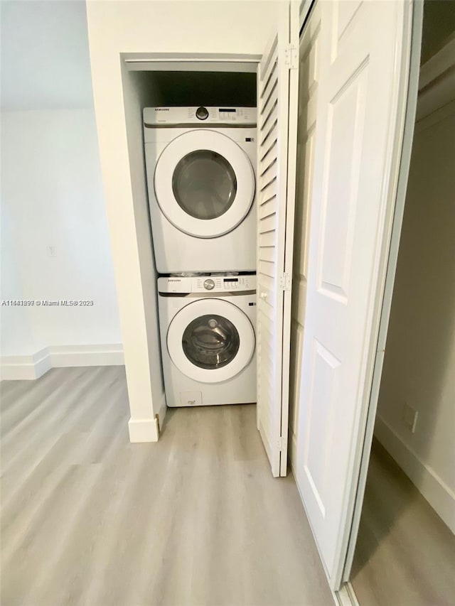 clothes washing area with light wood-type flooring and stacked washer and dryer