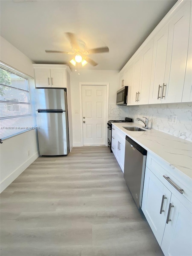 1005 NE 2nd St, Hallandale Beach, FL 33009 - kitchen featuring a sink, baseboards, white cabinetry, light stone counters, and appliances with stainless steel finishes
