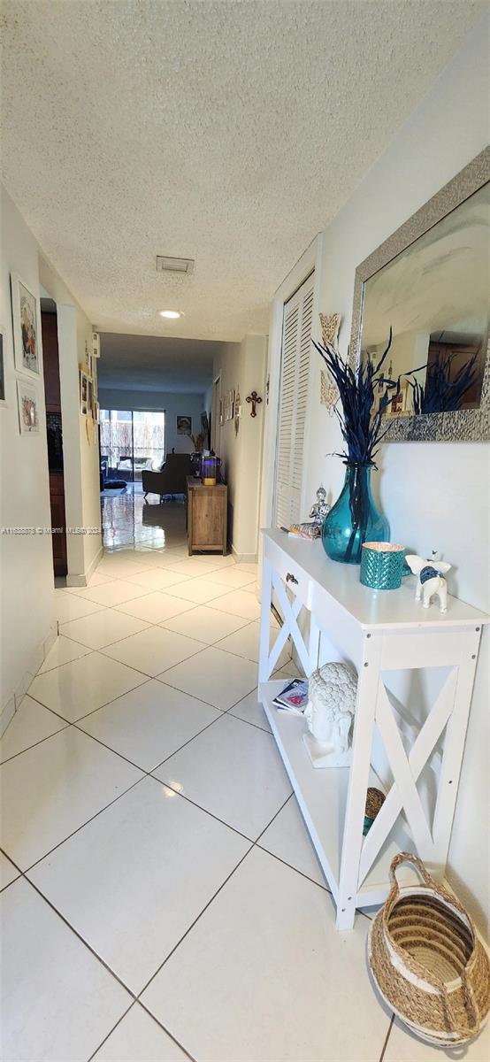 hallway with light tile patterned flooring and a textured ceiling