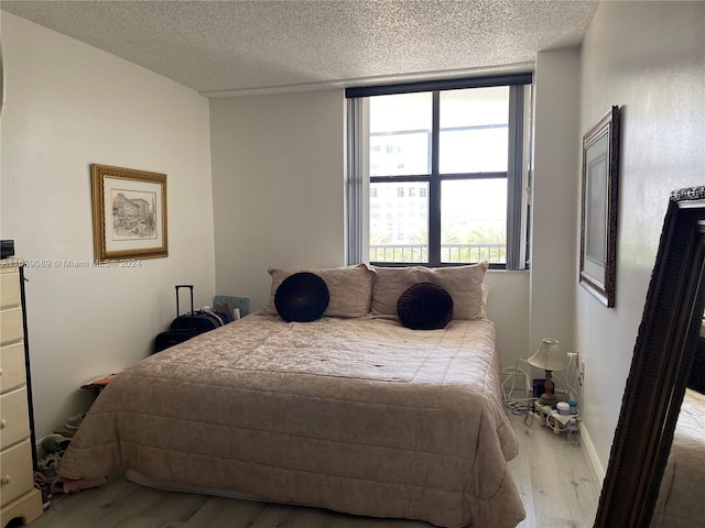 bedroom with a textured ceiling and light hardwood / wood-style flooring