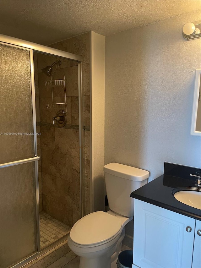 bathroom featuring a textured ceiling, an enclosed shower, vanity, and toilet