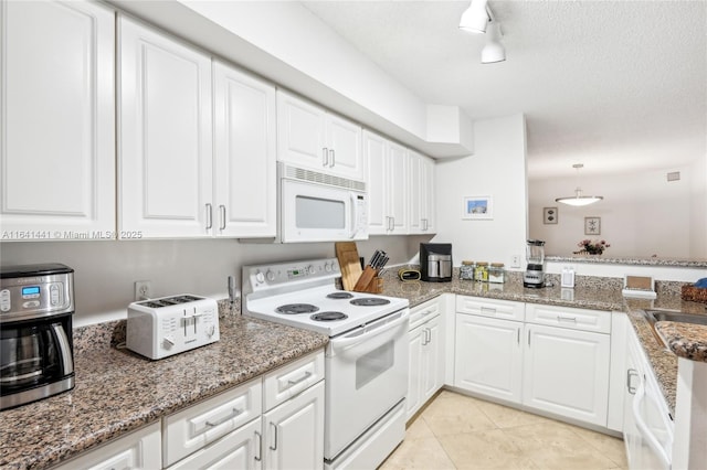 kitchen with a peninsula, white appliances, light tile patterned flooring, and white cabinetry