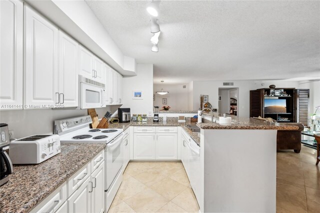 kitchen featuring white appliances, white cabinetry, and a peninsula