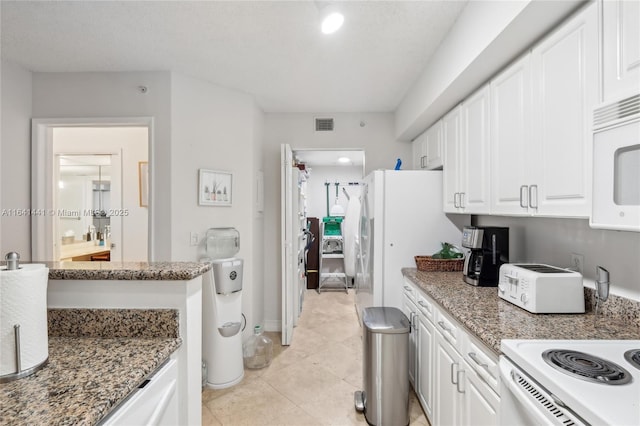 kitchen with white appliances, visible vents, dark stone counters, and white cabinets