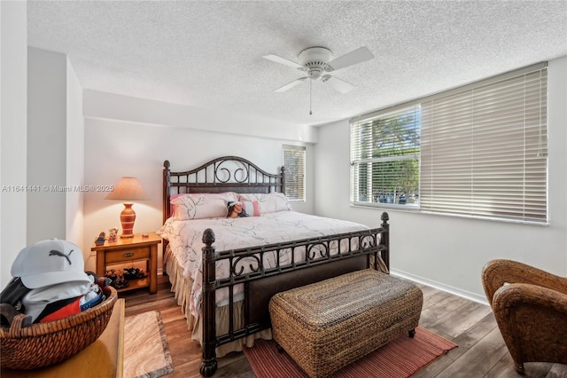 bedroom with ceiling fan, a textured ceiling, baseboards, and wood finished floors