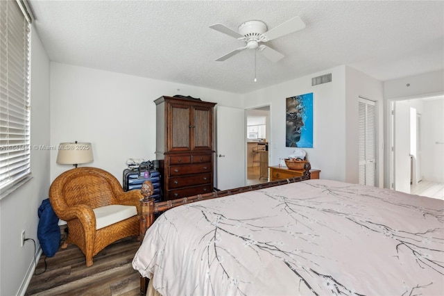 bedroom featuring a textured ceiling, wood finished floors, visible vents, a ceiling fan, and a closet