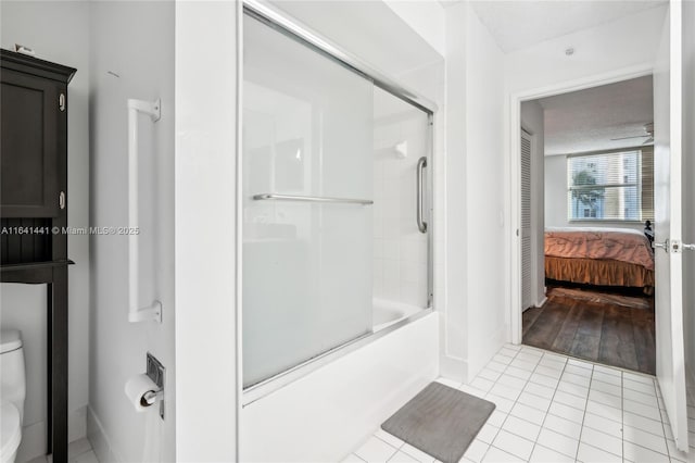 bathroom with bath / shower combo with glass door, tile patterned flooring, toilet, and ensuite bathroom