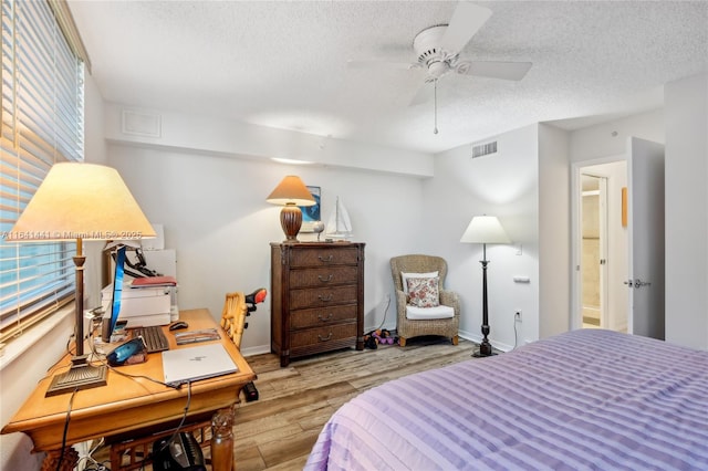 bedroom featuring a ceiling fan, baseboards, a textured ceiling, and light wood finished floors